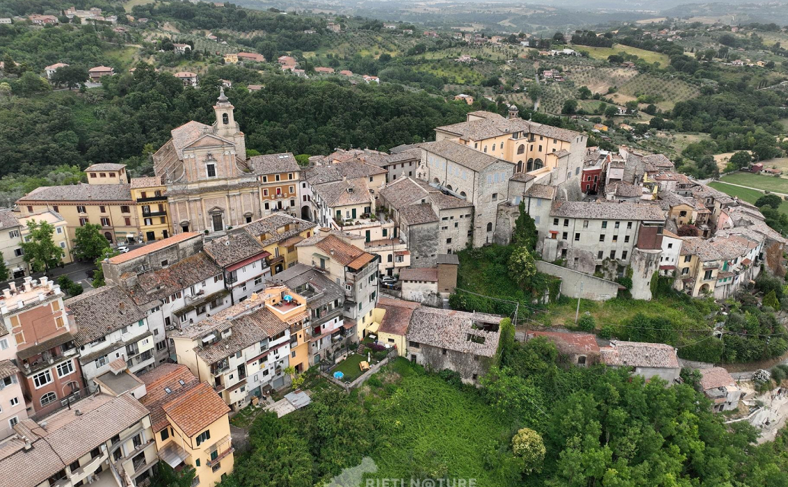 Veduta aerea del centro storico di Poggio Mirteto, con la chiesa principale e i tetti delle case immerse nel verde delle colline sabine.