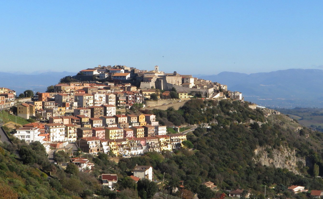 Veduta panoramica del borgo di Sant'Oreste, arroccato su un colle, con le sue case che si estendono verso la cima dominata da una chiesa.